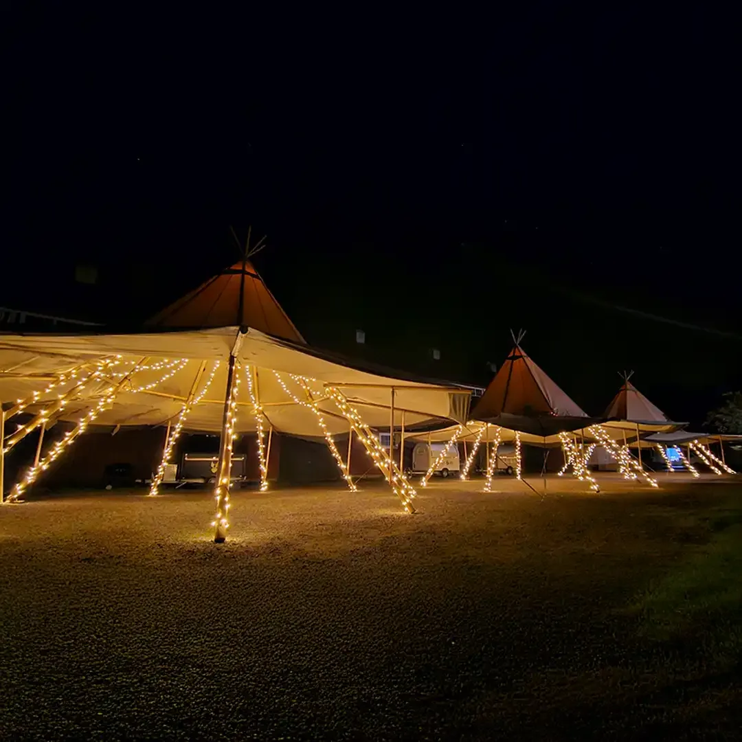 En tipi lyser varmt mod en mørk nattehimmel