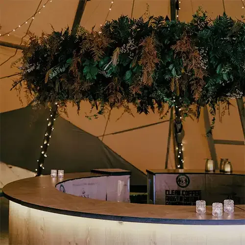 Stor ring dekoreret med grønt og blomster over en rund bar