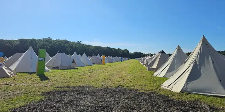 Rækker af sovetelte på en grøn mark ved virksomhedscampen i Sverige