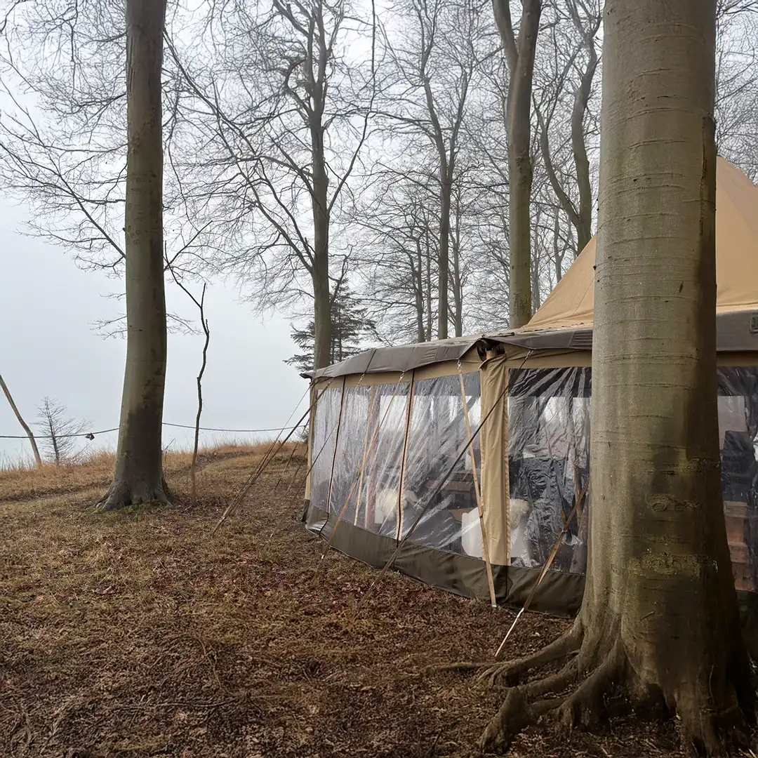 Et tipi-telt placeret ved skovens kant på Langeland, med udsigt over vandet. Det perfekte sted til udendørs events, naturoplevelser, bryllupper og firmaarrangementer i unikke omgivelser.