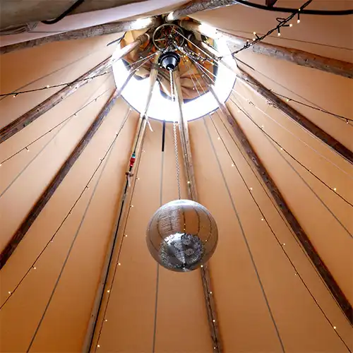 En tipi med en hængende diskokugle og lysdekoration, klar til en festlig aften