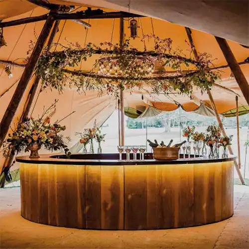 En rund bar med smukke blomster og stemningsfuld belysning i en tipi til fester