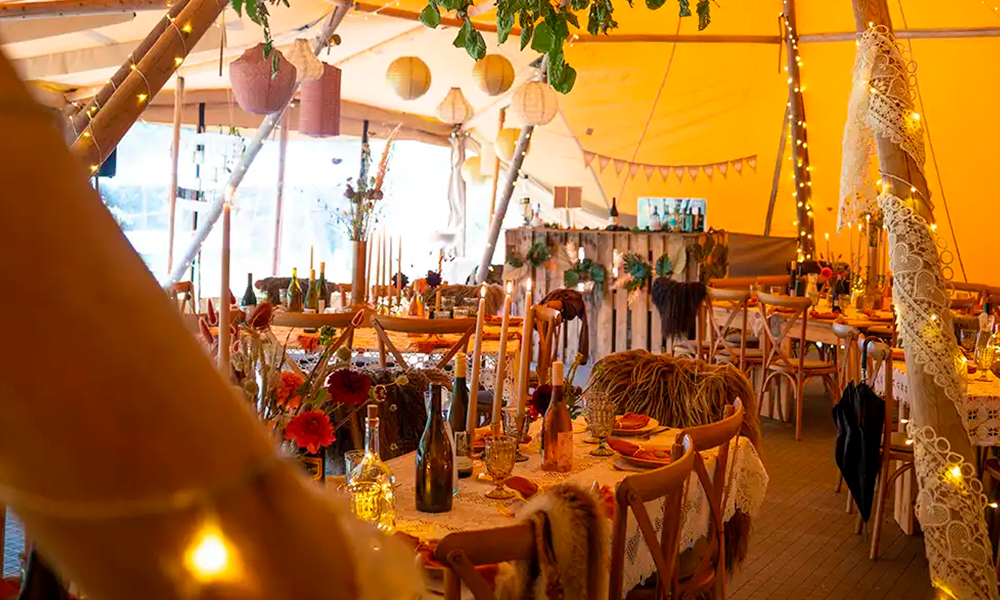 Hyggeligt bryllup med rustik dekoration, levende lys, lyskæder og vintage detaljer inde i et smukt tipi-telt