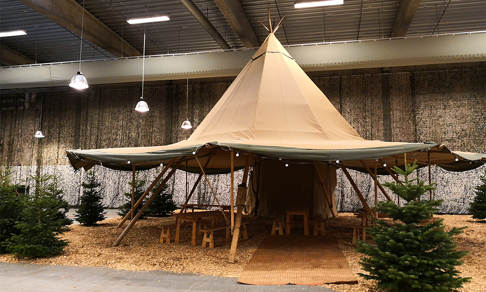 Tipi-telt opsat i en stor hal med hyggelig skovtema-dekoration, ideelt til julefrokoster, firmaevents og udstillinger – TipiogCo