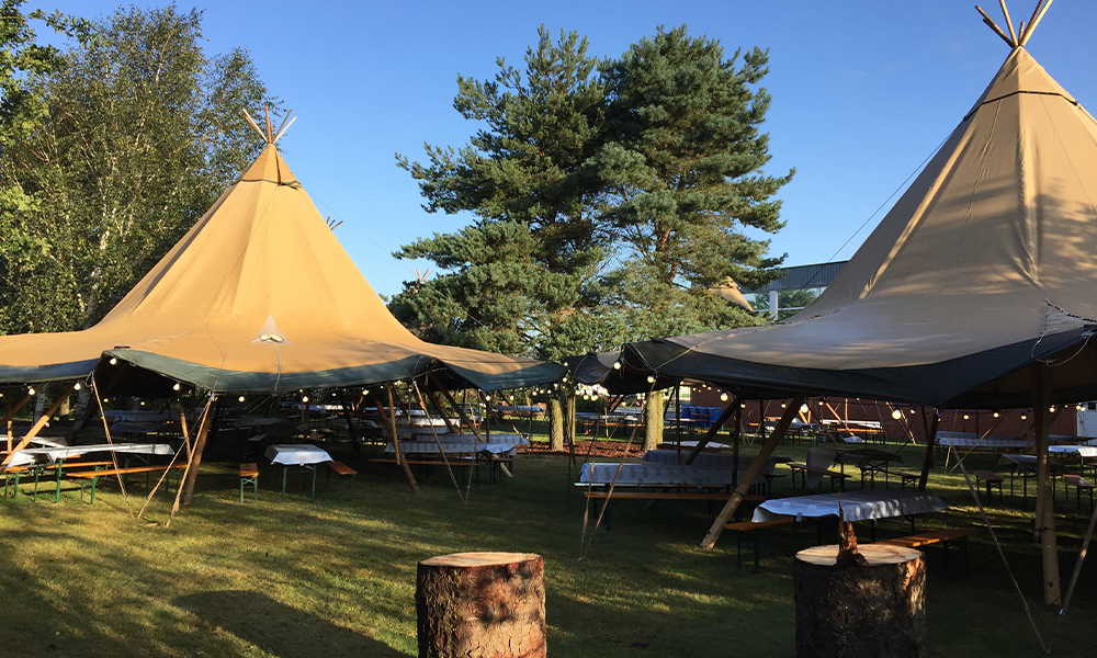 Store tipi-telte med bordopstilling i grønne omgivelser, perfekt til firmafester, events og konferencer i det fri – TipiogCo