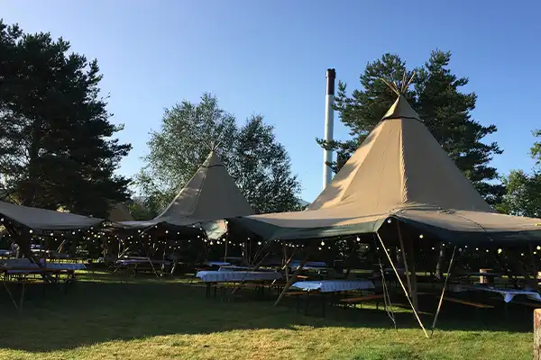 Tipi-telte med borddækning i grønne omgivelser, perfekt til firmafester, konferencer og udendørs arrangementer med eksklusiv stemning – TipiogCo