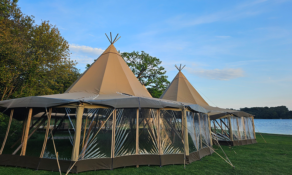 Store tipi-telte med panoramavinduer opsat i naturskønne omgivelser ved en sø, ideelle til bryllupper og events – TipiogCo.