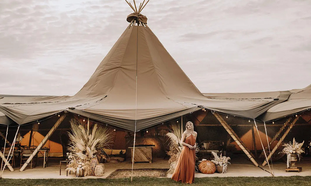 Stort tipi-telt dekoreret i boho-stil med pampasgræs, lyskæder og rustik indretning, perfekt til bryllupper og events – TipiogCo.