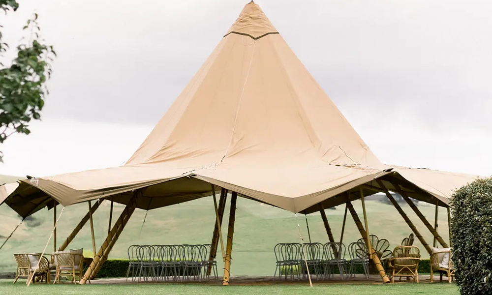 Elegant tipi-telt opsat i naturskønne omgivelser med stilfulde siddepladser, ideelt til bryllupper, fester og eksklusive events – TipiogCo.