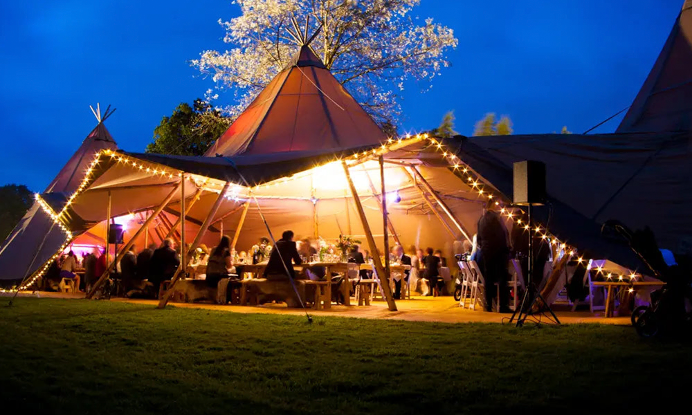 Tipi-telt oplyst af lyskæder skaber en magisk atmosfære til en festlig aften med gæster, god stemning og hyggelige omgivelser – TipiogCo.